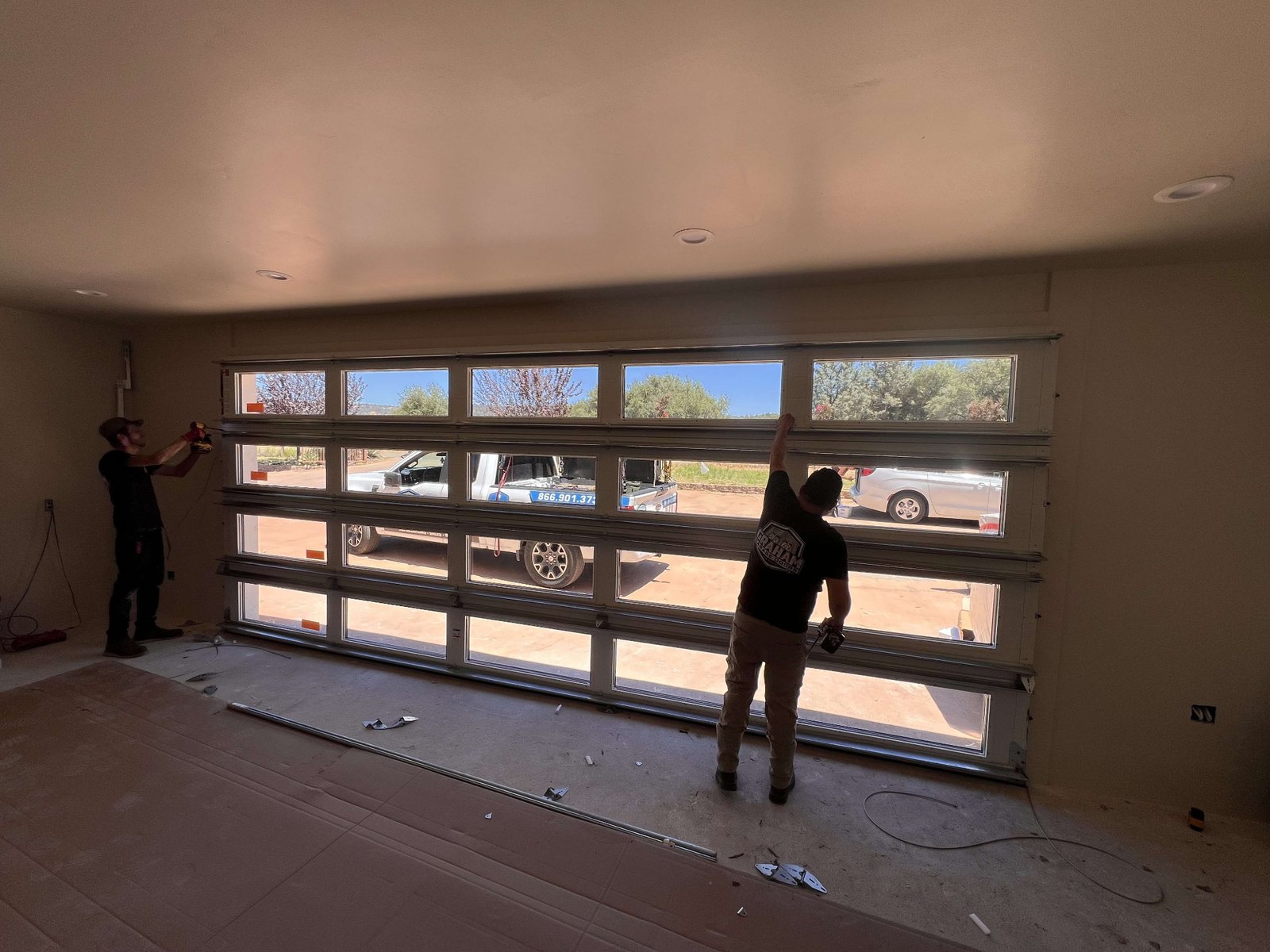 Two Graham Garage Doors technicians installing a full-view residential garage door from inside a garage